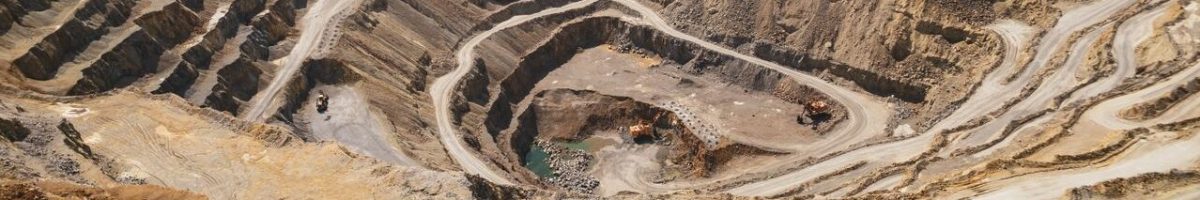 Aerial view of a large open-pit mine with terraced excavation during summer.